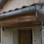 Avancée de toit au-dessus d’une porte, gouttière et raccord d’étanchéité